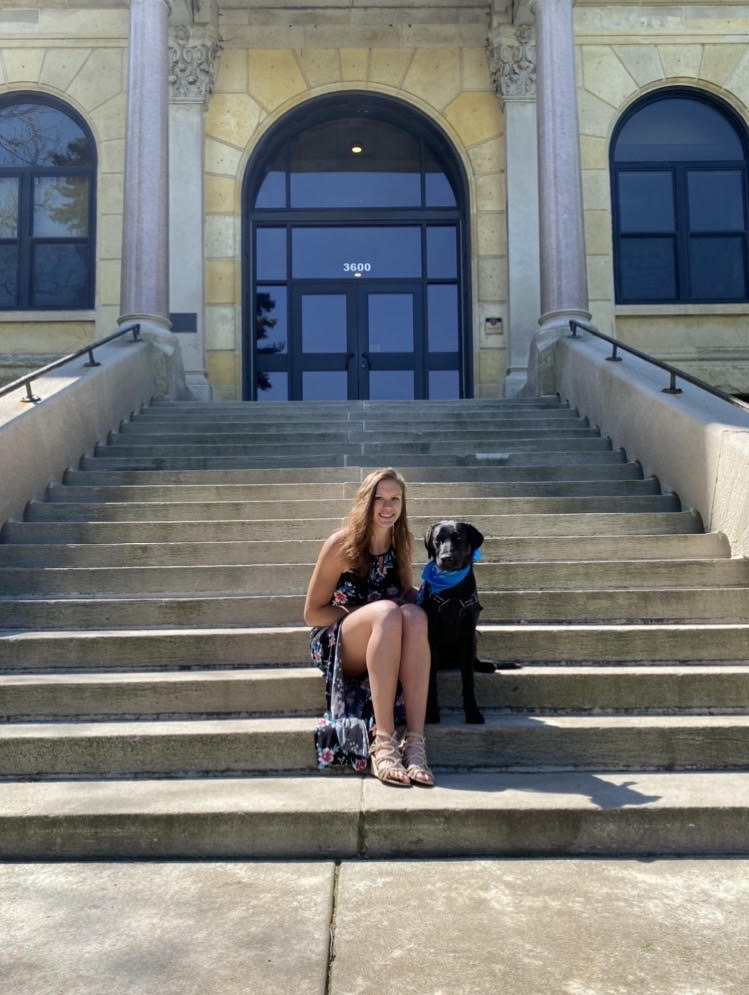 Sarah and service dog Clint sitting on concrete steps